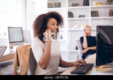 Young happy mixed race businesswoman with headset Stock Photo
