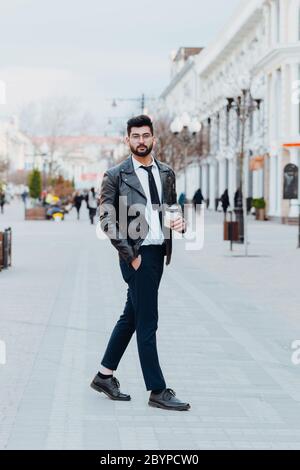 Stylish bearded Indian man drinking takeaway coffee on the street. Stock Photo