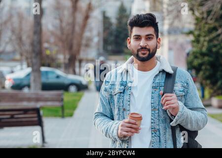 Stylish bearded Indian man drinking takeaway coffee on the street. Stock Photo