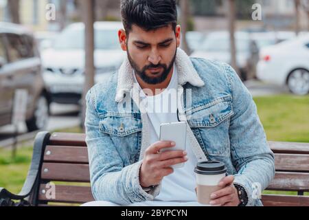 Bearded Indian man on the street using the application in his smartphone. Stock Photo