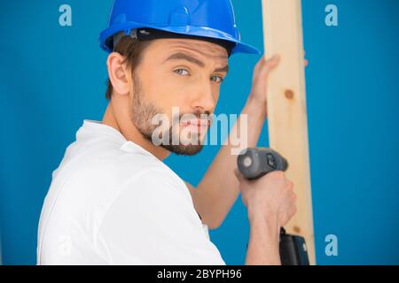Builder using a drill looking at the camera Stock Photo