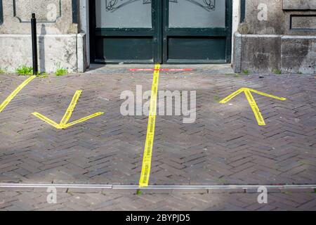 Entrance to a pub with yellow sticker tape reminding people in Dutch to keep social distancing 1,5 meter and in which direction to enter and exit Stock Photo