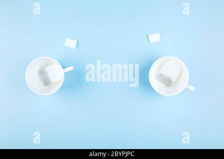 Cups of tea and tea bags on blue background. Top view, copy space. Food background Stock Photo