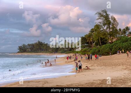 People on the beach at dusk at Sunset Beach Park on the north shore of Oahu, Hawaii Stock Photo