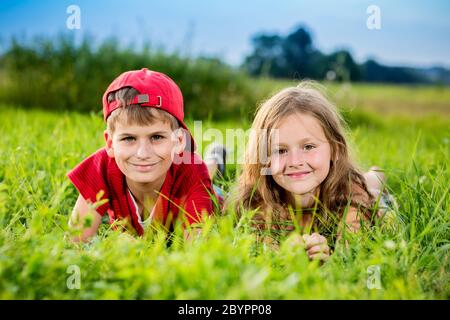 Cut boy and a girl are resting on the green grass in summer Stock Photo