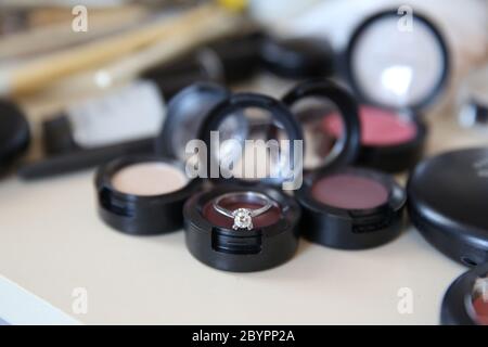 Close up shot of a diamond wedding ring shining on colorful eye shadows Stock Photo