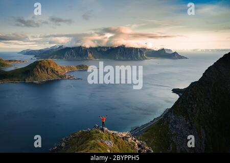 Tourist stand alone on a rock and watching sea horizon within sunset. Rocky part of path with view into distance. Stock Photo