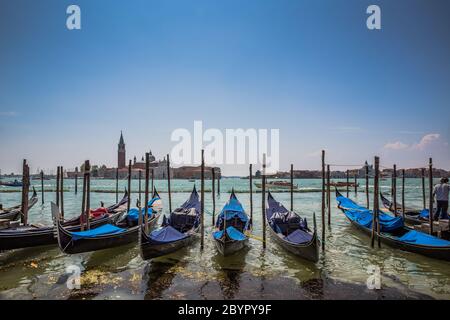 Two traditional Grand Canal gondolas moored to pier, the Church and Island of San Giorgio Maggiore and Giudecca in the background, Venice, Italy Stock Photo