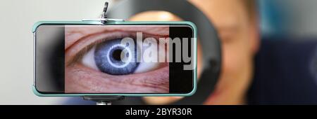 Man making video trying to shoot his own eye using modern smartphone camera Stock Photo