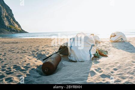 Plastic bottles and other trash on sea beach. During a vibrant summer sunset. Garbage and wastes on the beach of Atlantic ocean, Lofoten, Norway Stock Photo