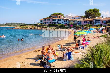 Porto San Paolo, Sardinia / Italy - 2019/07/18: Tourists enjoying sunbath at Porto San Paolo resort town beach - Spiaggia di Porto San Paolo - at Cost Stock Photo