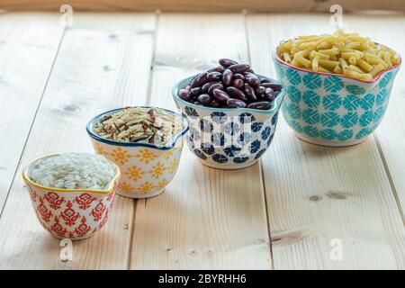 Dry rice, kidney beans and pasta in a ceramic pots on wooden background Stock Photo