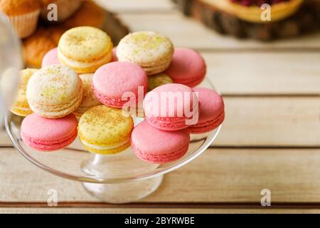 Closeup shot of colorful traditional french dessert macaroons on a glass plate placed on a table outdoors Stock Photo