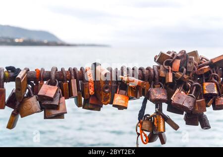 Rusty locks on a bridge, with the Mediterranean sea in the background Stock Photo