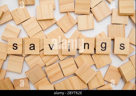 Wood letter tiles spelling word SAVINGS lying on a pile of tiles Stock Photo