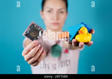 A young girl holds out a condom and a handful of children's toys into the camera Stock Photo