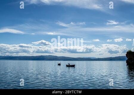 Fisherman fishing alone on Lake Ohrid on a cloudy summer day, City of Ohrid, Republic of North Macedonia (FYROM) Stock Photo