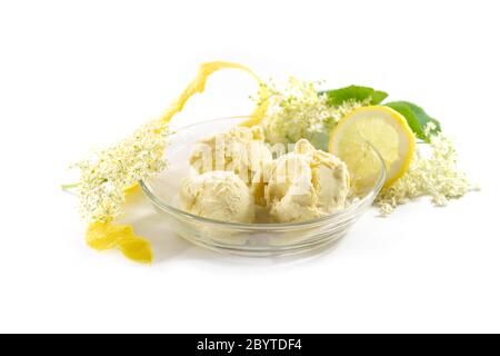 Ice cream from elderberry flowers in a glass bowl, lemon peel and slices and some fresh blossoms isolated on a white background, copy space, selected Stock Photo