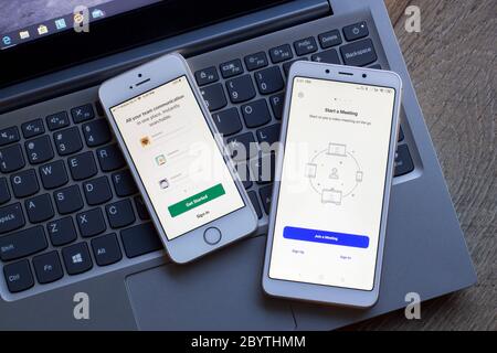 Team communication and collaboration tools login pages seen on smartphones. Left: Slack. Right: Zoom Cloud Meetings. Stock Photo
