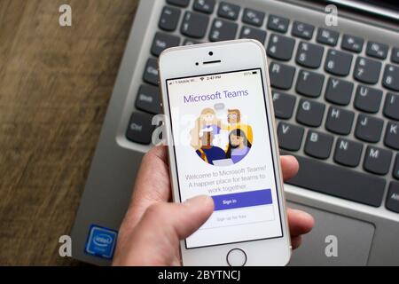 A user opens the Microsoft Teams mobile app. Teams is a unified team communication and collaboration platform with workplace chat, video meetings, etc. Stock Photo