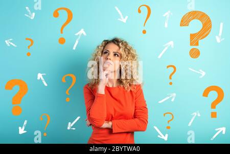 Confused and pensive expression of a girl with many questions . cyan colored background Stock Photo