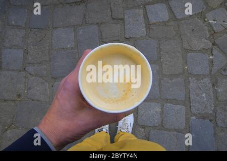 Morning coffee on the city street. Hands of the young man holding disposable cup with hot coffee. Stock Photo