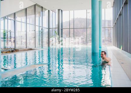Shot of a handsome young happy man in the indoor swimming pool Stock Photo