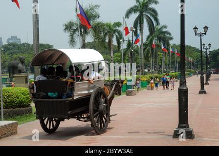 Horse and coach rides along walkway in Rizal Park, formerly Lunetta Park, Manila, Philippines, Asia. Stock Photo