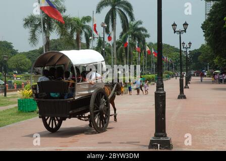 Horse and coach rides along walkway in Rizal Park, formerly Lunetta Park, Manila, Philippines, Asia. Stock Photo