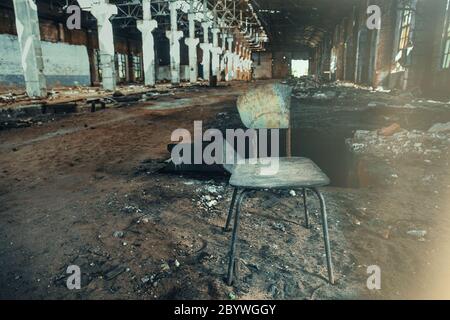 Old broken chair inside dirty abandoned ruined industrial building, toned Stock Photo