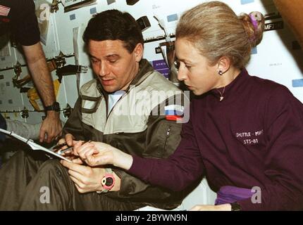 STS081-357-020 (12-22 Jan. 1997) --- Astronaut Marsha S. Ivins, STS-81 mission specialist, compares notes with cosmonaut Valeri G. Korzun, Mir-22 mission commander. The two were involved with the transfer of supplies from the Space Shuttle Atlantis to Russia's Mir Space Station, during the docking mission. Stock Photo