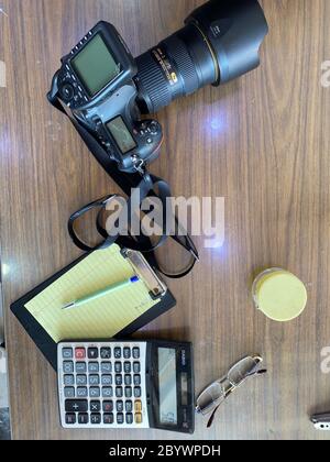 Camera on Table with note pad and calculator with eye spectical on wooden table Stock Photo