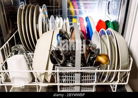 Clean dishes and cutlery inside a dishwasher at home. Stock Photo