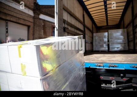 White cardboard boxes transported on pallets by a merchandise delivery truck. Stock Photo