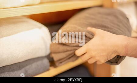 Male hand choosing sheet of fabric or textile. Group of Multi-colored Earth Tone fabric swatch for bed sheet or furniture finishing material. Home dec Stock Photo
