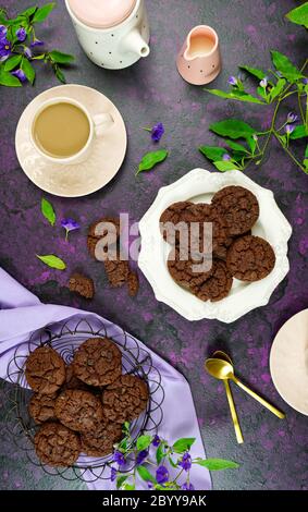 Serving freshly baked double chocolate chip homemade cookies on pink tray with tea and coffee, creative concept flat lay. Top view overhead vertical o Stock Photo