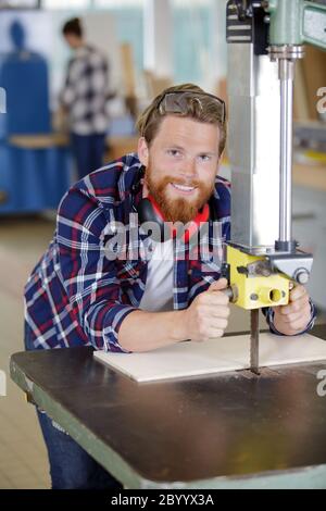 happy worker sawing board for furniture in carpentry Stock Photo