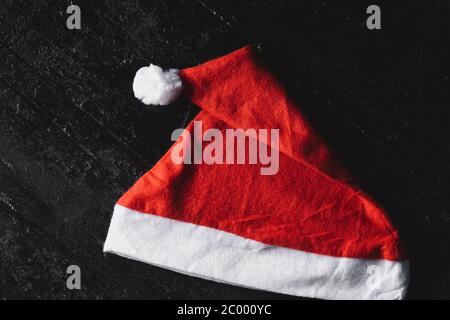 Red Santa Claus cap on dark wooden background. Christmas/New Year concept. Stock Photo