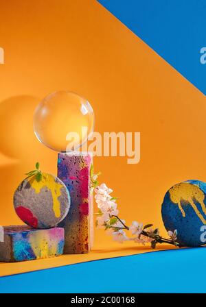 Cherry blossom with concrete blocks and glass sphere, yellow and blue modern still life Stock Photo