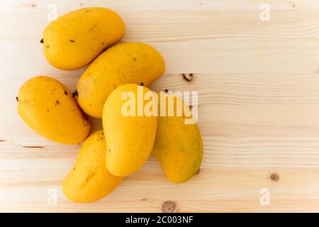 Yellow mangoes close up. Fresh ripe organic fruits on wooden background, flat lay, copy space Stock Photo