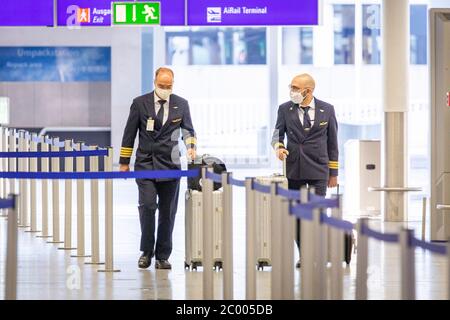 Pilots wearing face masks are walking through the nearly empty Frankfurt Airport during the lockdown caused by the COVID-19 virus. Worldwide, the air traffic industry is heavily impacted by the massive drop in traffic. Stock Photo