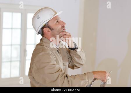builder thinking about something while holding clipboard Stock Photo
