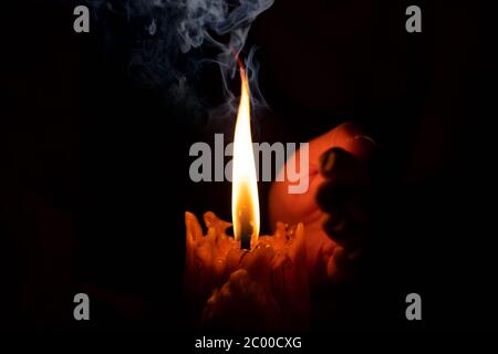 Hand protecting candle light from the wind in darkness on black background Stock Photo