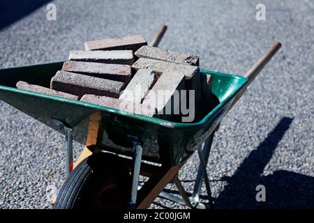 a green wheelbarrow filled with curbs from the front Stock Photo