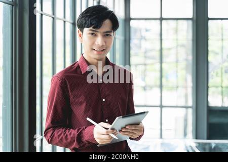 Men are smiling and cheerful. Using the tablet and holding it on hand. He use tablet to work, check emails, teleconferences, or social networks. Durin Stock Photo