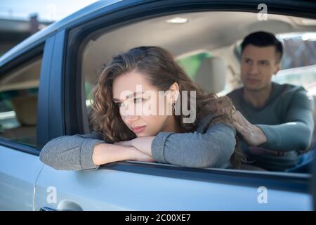 Offended turned away woman and attentive man sitting in car Stock Photo