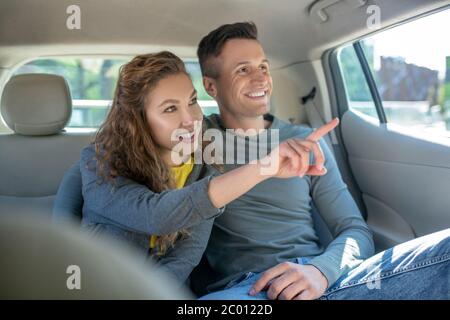 Woman showing hand out window and hugging her man in car Stock Photo