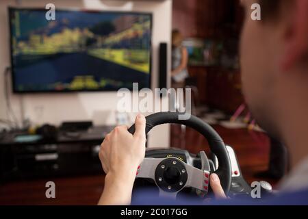 Man playing racing game with steering wheel simulator Stock Photo