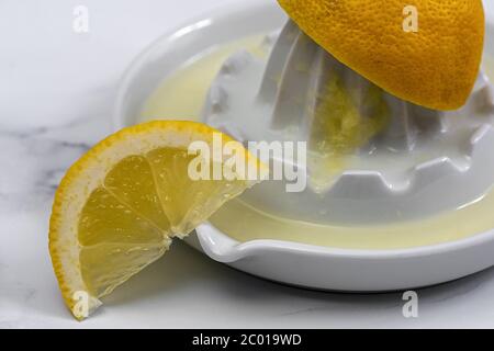 half a lemon squeezed with a porcelain citrus press with a lemon wedge Stock Photo