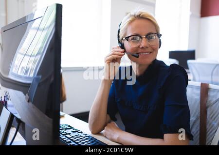 Mixed race woman talking on an earpiece while smiliing and looking at camera Stock Photo
